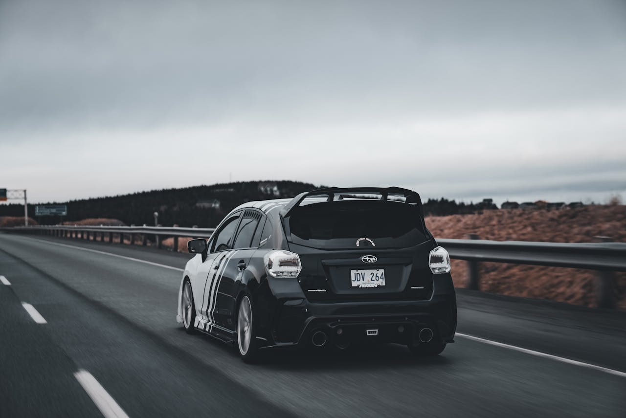 A black car driving down the road on a highway